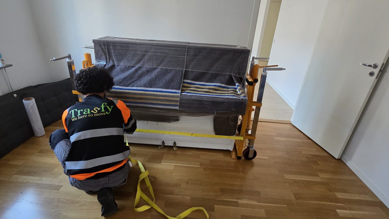 En flyttare från Trasfy plastar in och spänner fast en soffa inför transport