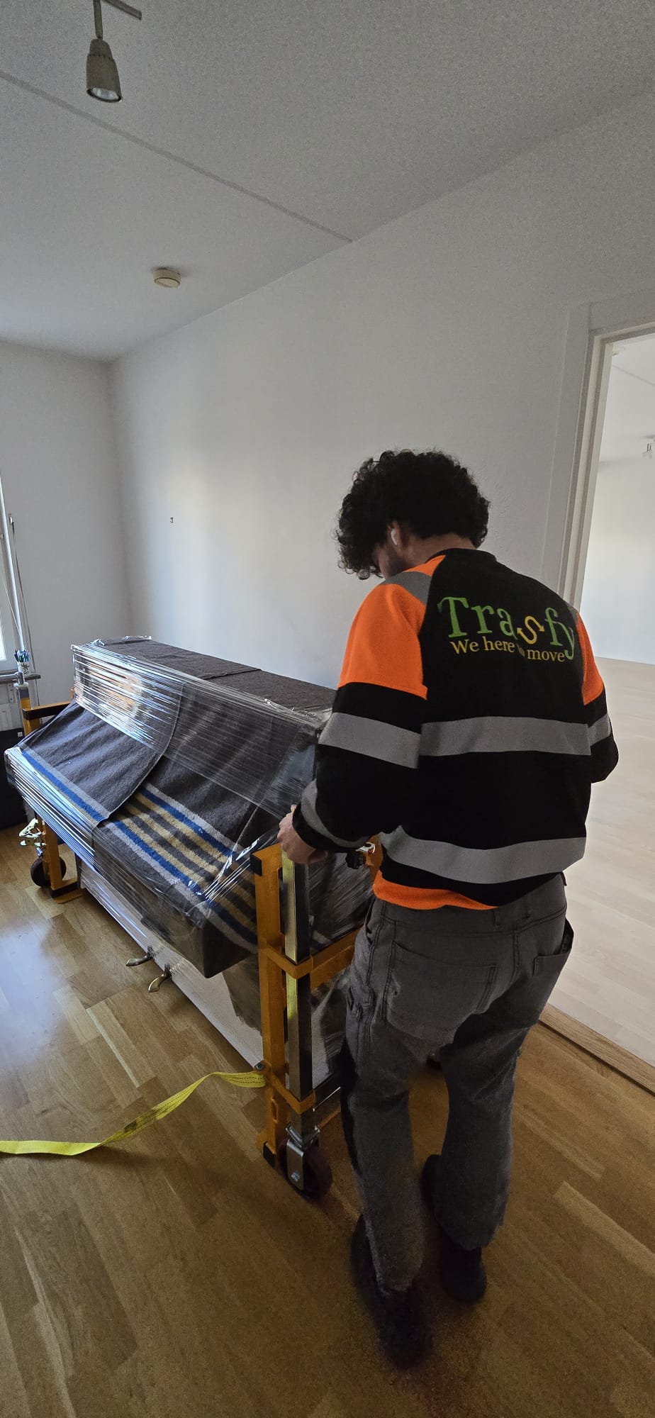 En flyttare kör en inplastad soffa på pirra genom en tömd lägenhet